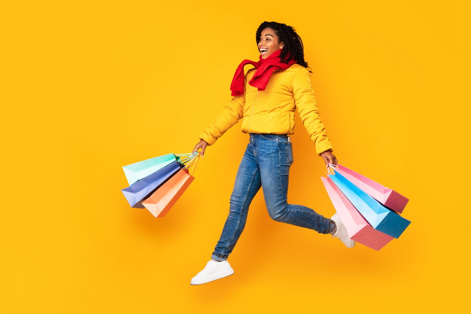 Joyful shopper leaps, colorful bags.
